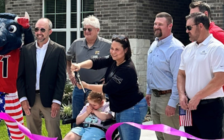 A group of people posing with a person in a garment.