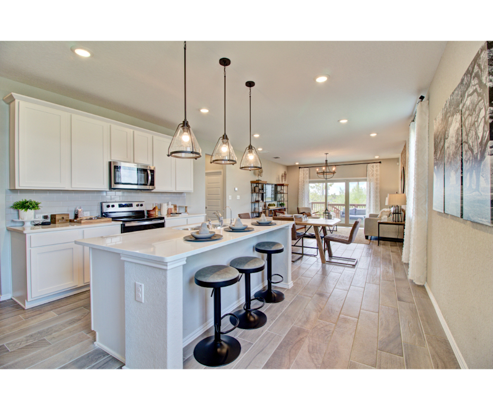 Kitchen with white cabinets, counters, and barstools at island